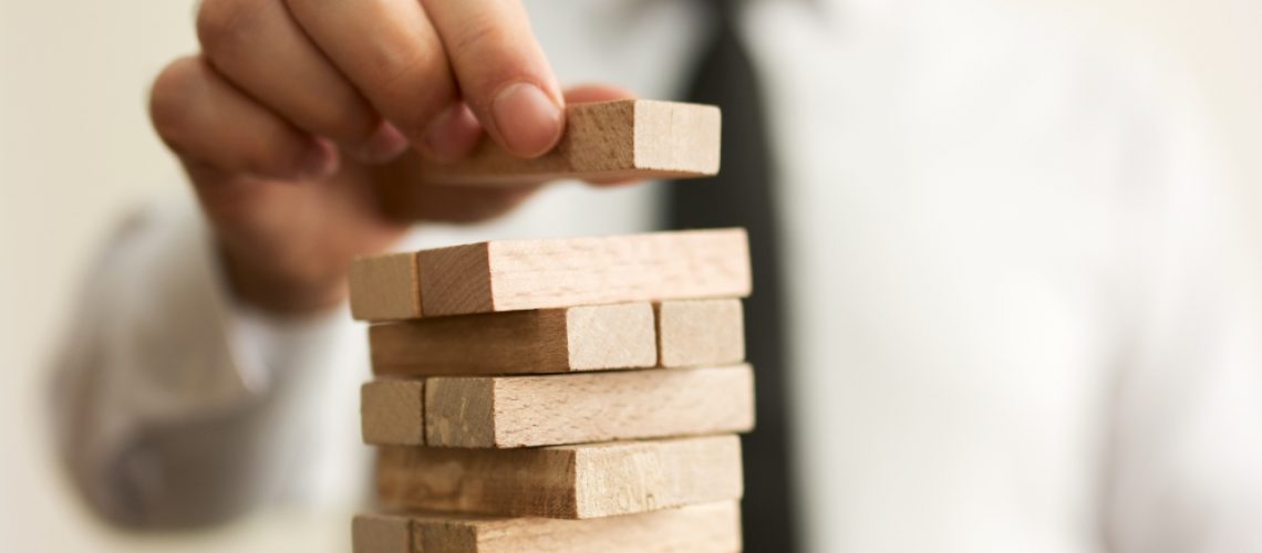 Businessman putting last block to the tower